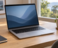 Illustrative silver laptop on a bright home-office desk beside a notebook and cup
